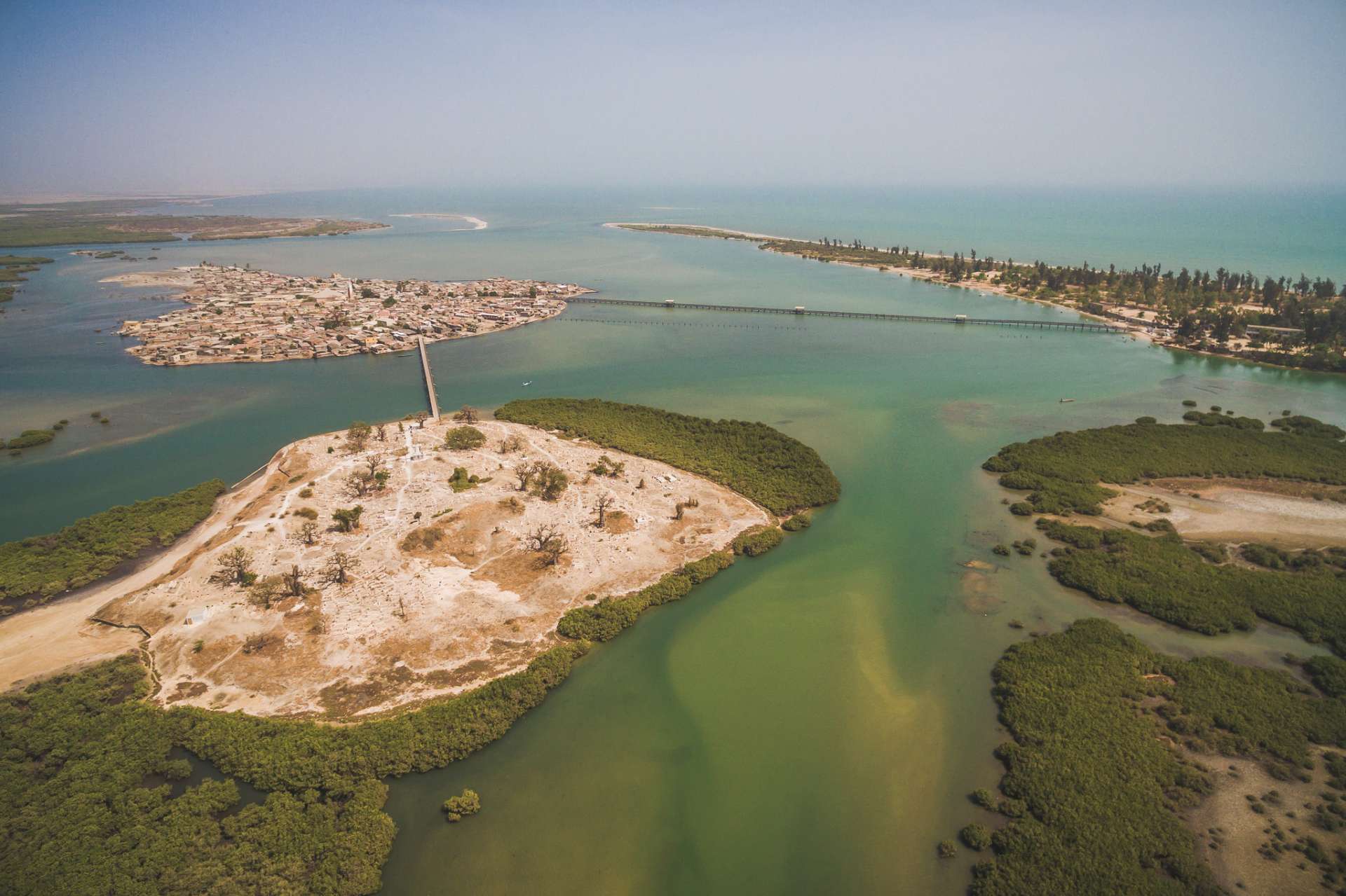 Joal se trouve sur le continent et Fadhiout sur une île artificielle constituée d’amoncellements de coquillage et reliée à la côte par un pont en bois qui enjambe la mangrove.